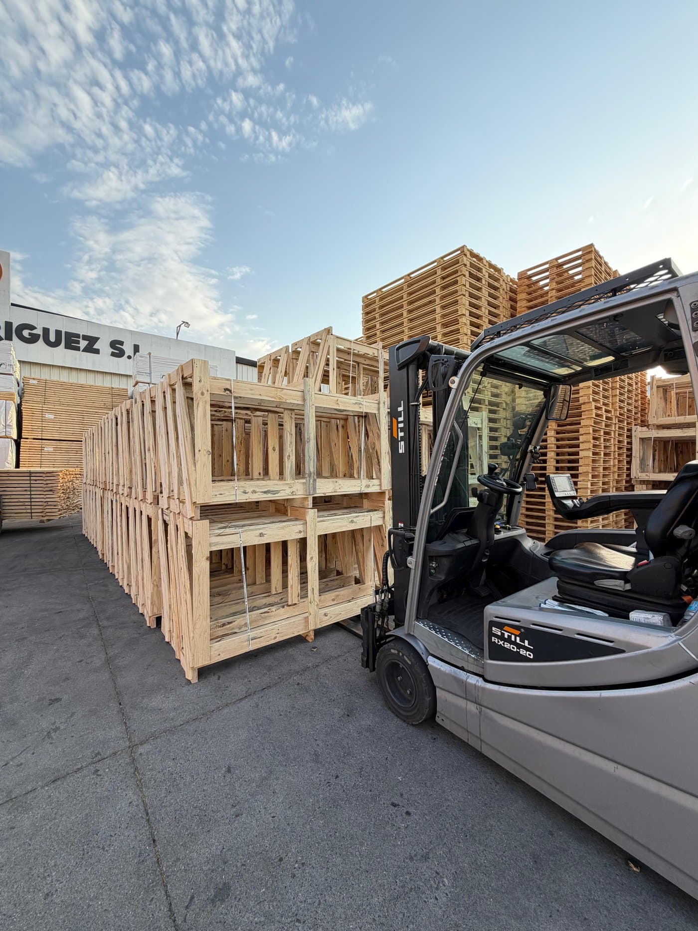 Carretilla elevadora moviendo cajas de madera fabricadas a medida en el patio de Palets Rodríguez, S.L.